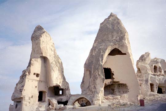 Two, peaked rock formations with doors and windows carved into them