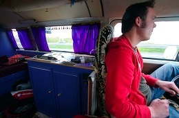 A man in a red shirt driving a van