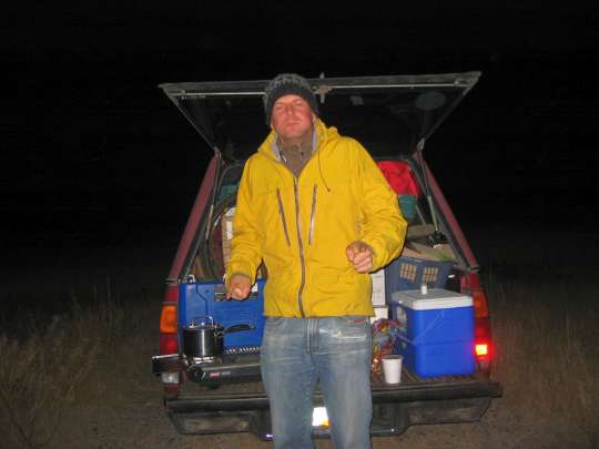 Man in yellow jacket next to pickup truck tailgate