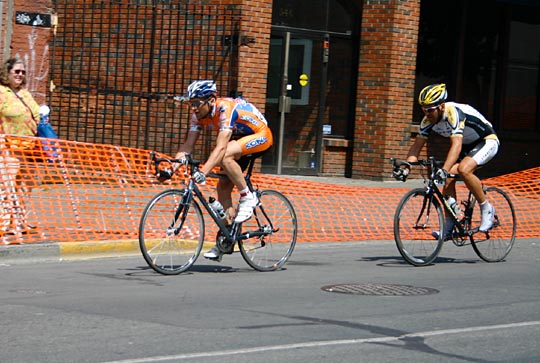 Two bike riders racing down a road