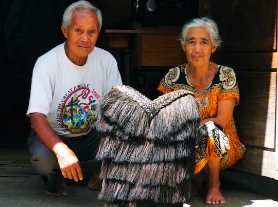 Photograph of two elderly people with the hunter backpack or bango in front of them