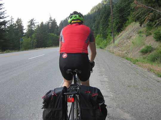 Man in red jersey ridng a bicycle, viewed from behind