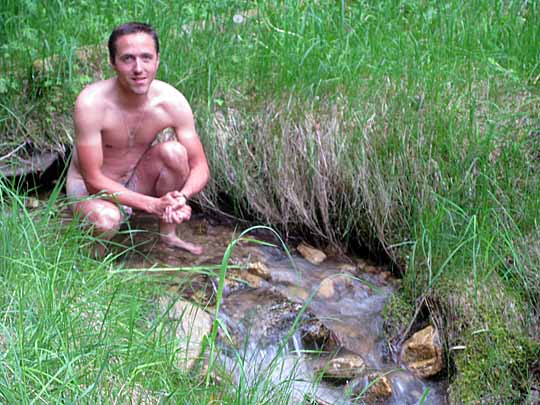 Naked man bathing in small stream