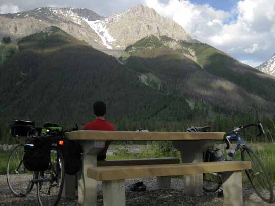 Man sitting at picnic table overlooking scenic mountains