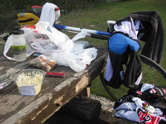 Picnic table with groceries, bicycle and shorts