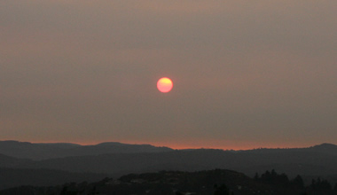 Dark red sun setting over hills