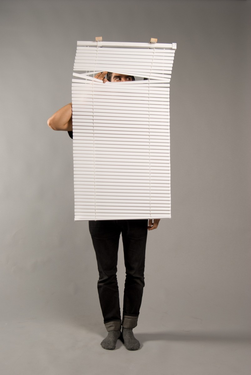 Man with venetian blinds hanging in front of his body, peaking through them